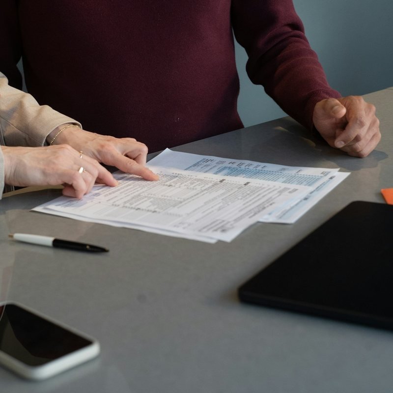 An insurance professional going through policy paperwork with a client at a desk.